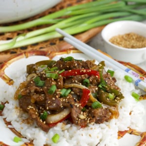 Easy pepper steak recipe on a bed of white rice on a bamboo plate