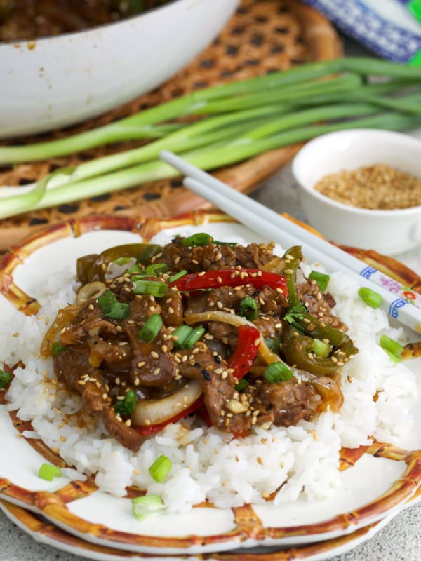 Easy pepper steak recipe on a bed of white rice on a bamboo plate