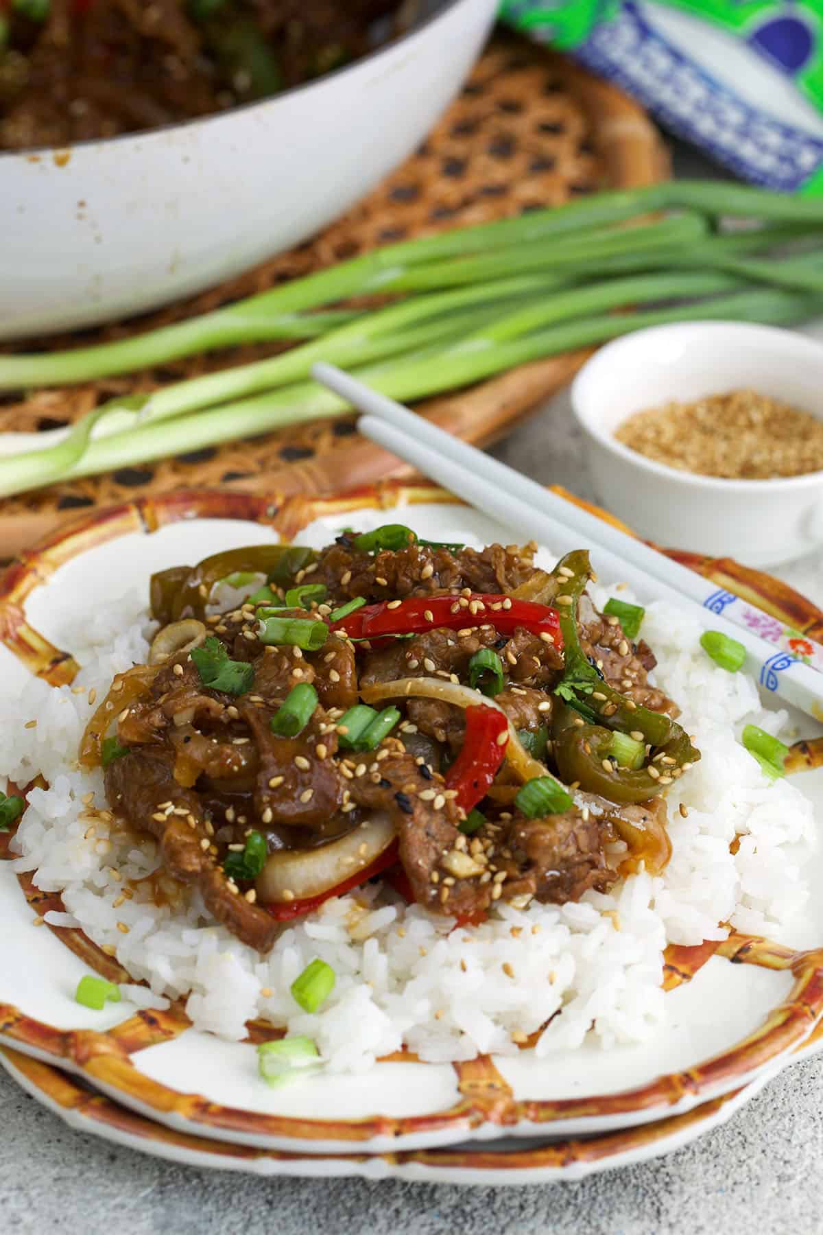 Easy pepper steak recipe on a bed of white rice on a bamboo plate